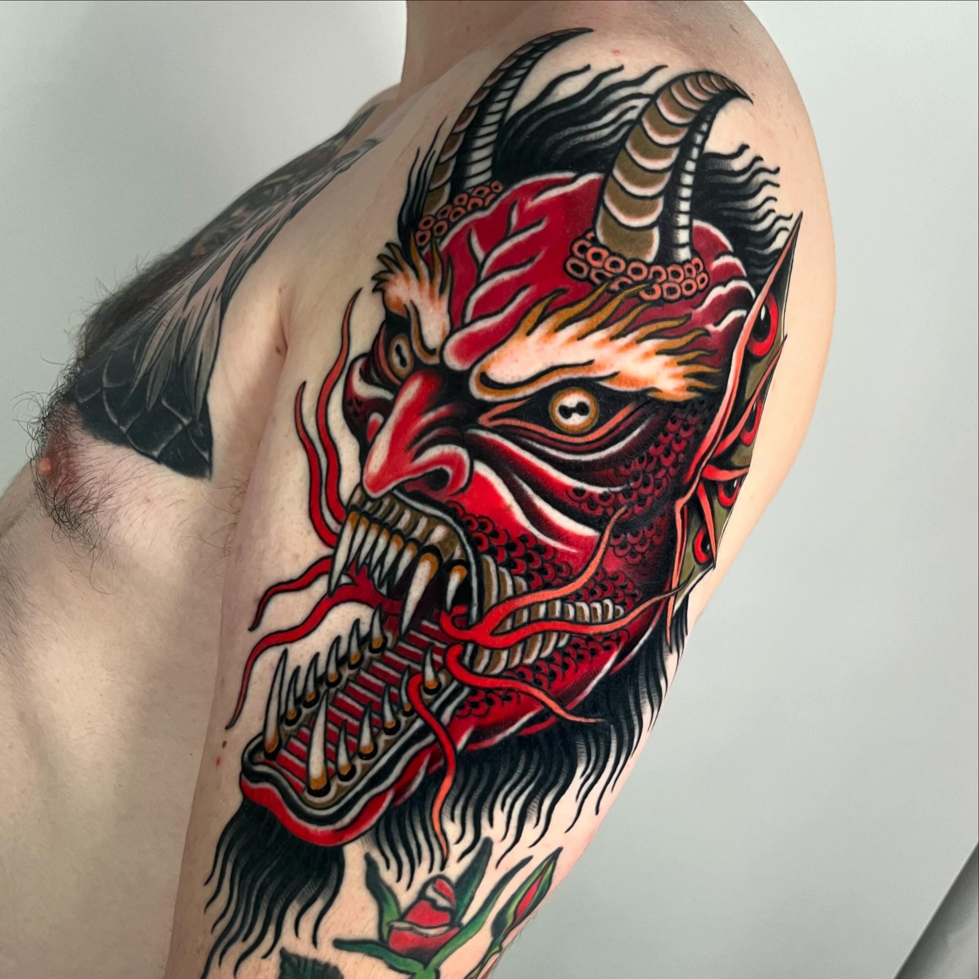 Demon mask American traditional tattoo on the shoulder by Sara Lewis