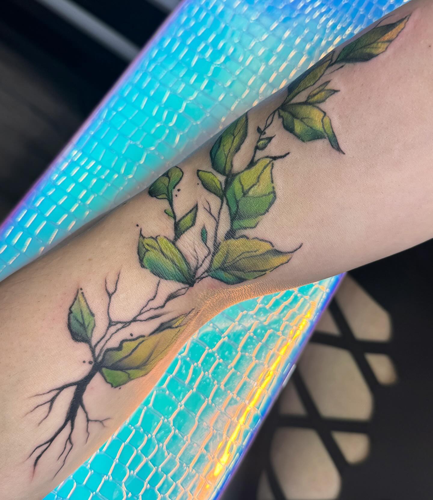Branch with leaves watercolor tattoo on the forearm by Robyn Mahon