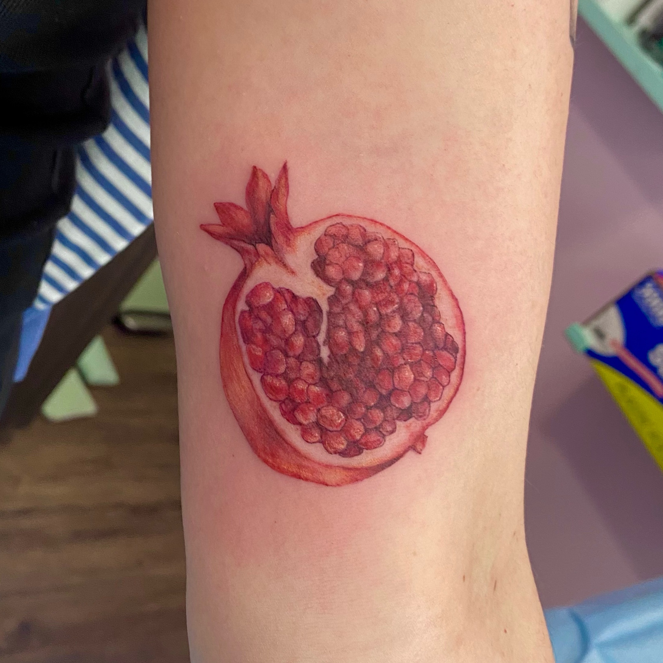 Pomegranate realism tattoo on the forearm by Emily Conner