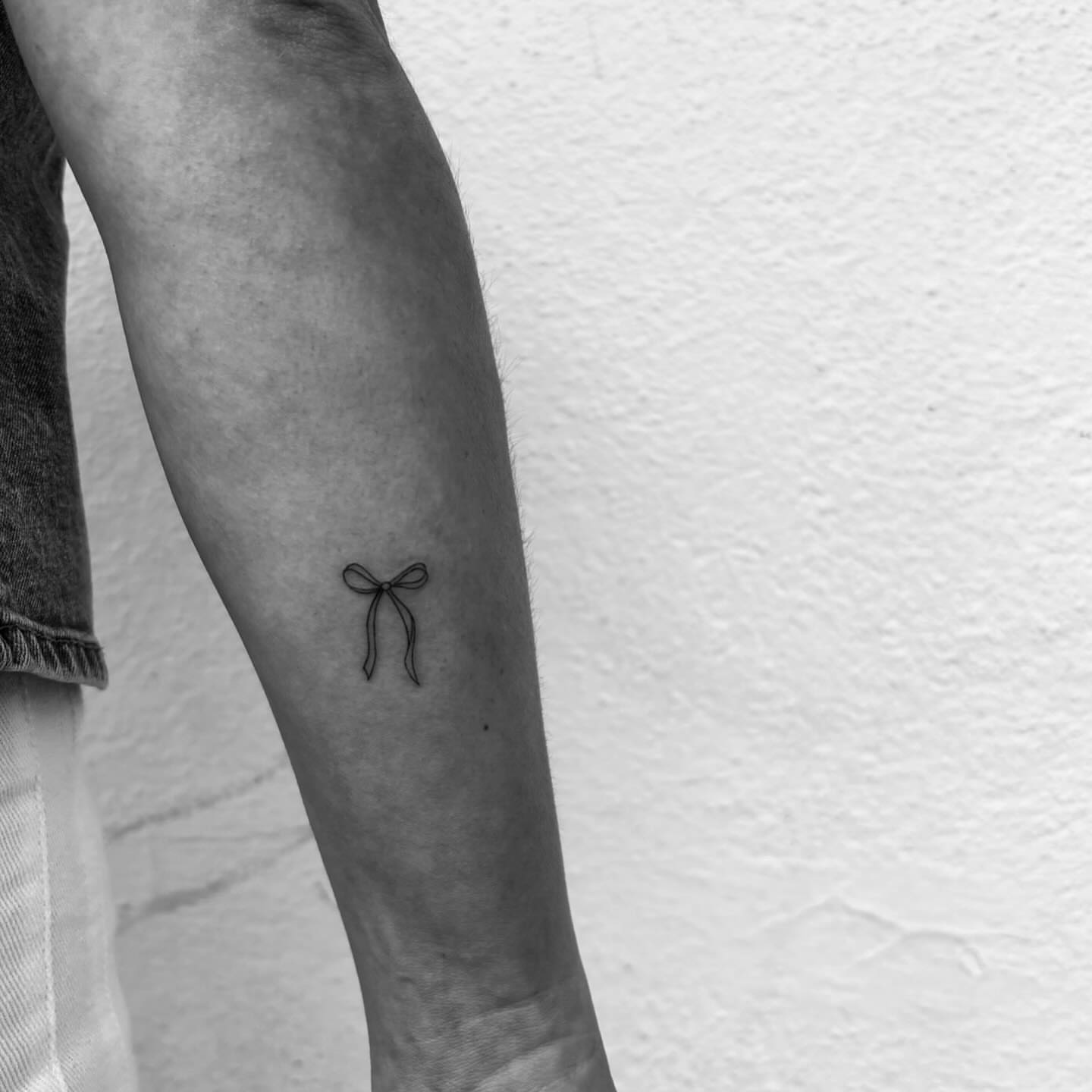 Bow minimalist tattoo on the forearm by Mady