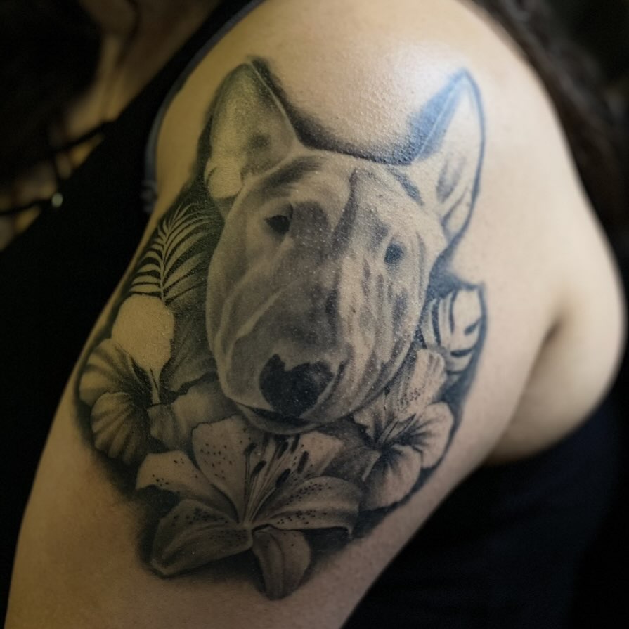 Bull terrier with flowers realism tattoo on the shoulder by Amber