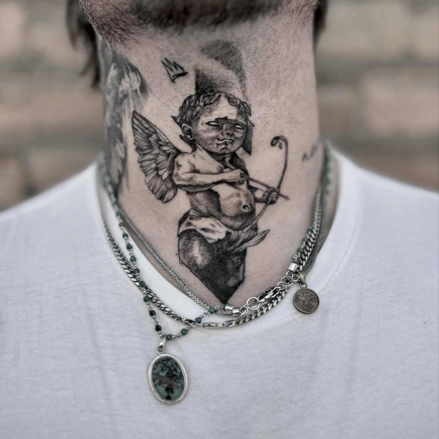 Cherub with bow black and grey tattoo on the neck by t a y l o r