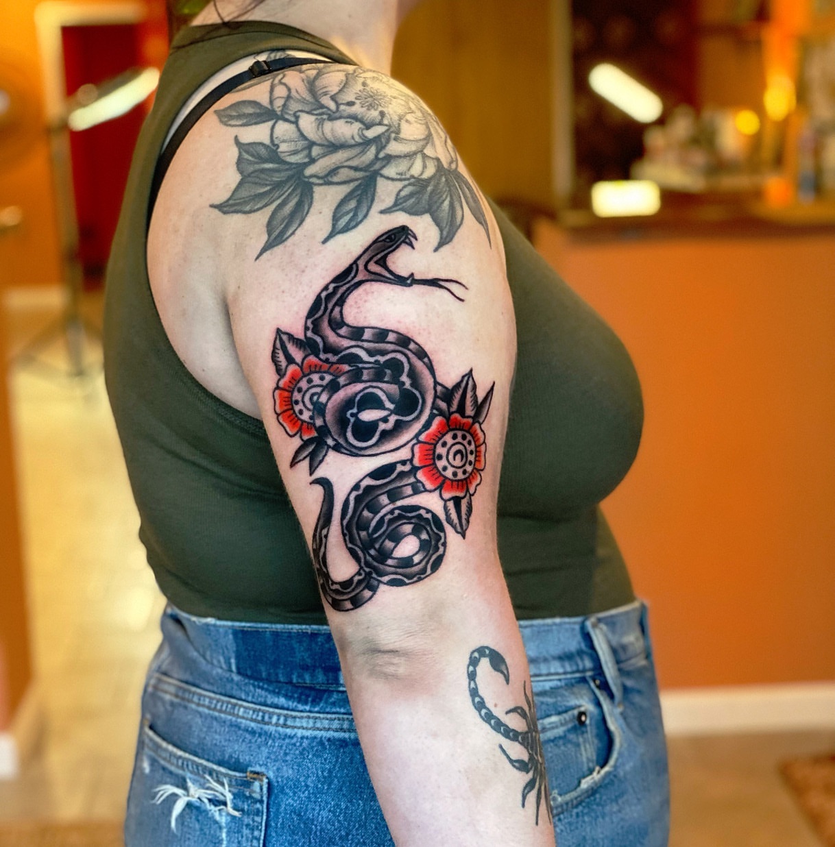 Snake and peony American traditional tattoo on the upper arm by Myka King