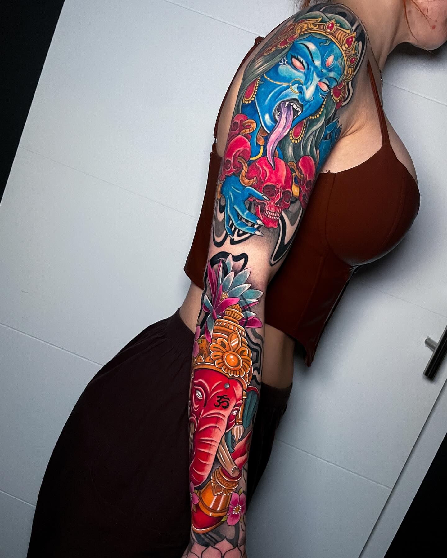 Mask and skull American traditional tattoo on the upper arm by Christian Pelaez