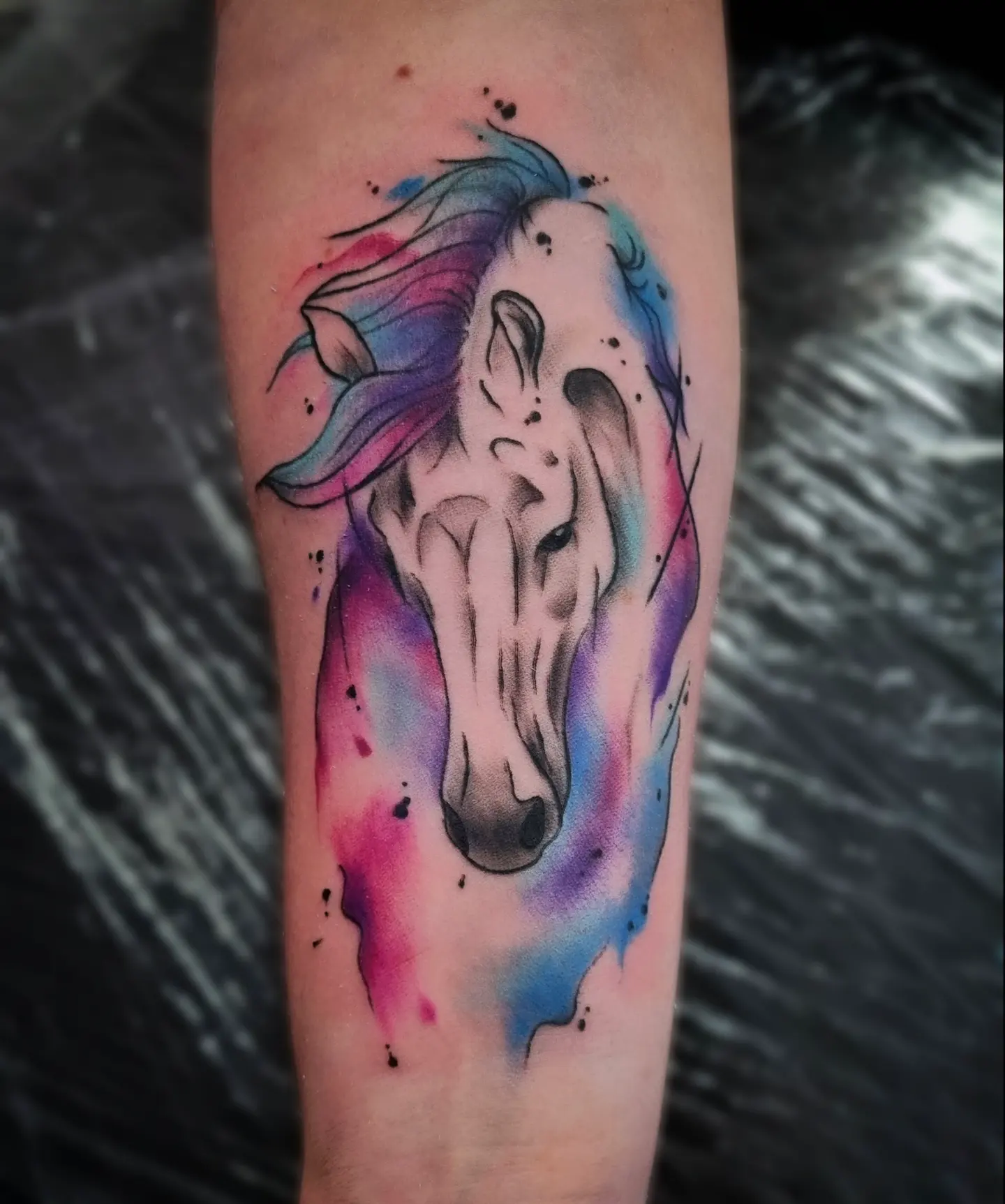 Horse head watercolor tattoo on the forearm by AntiheroTattoo
