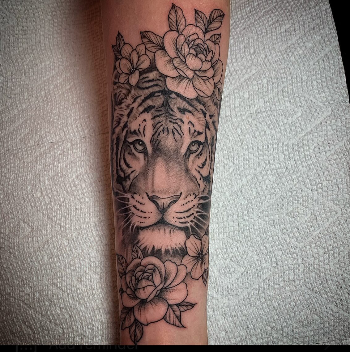 Tiger with flowers realism tattoo on the forearm by Brad Sterling