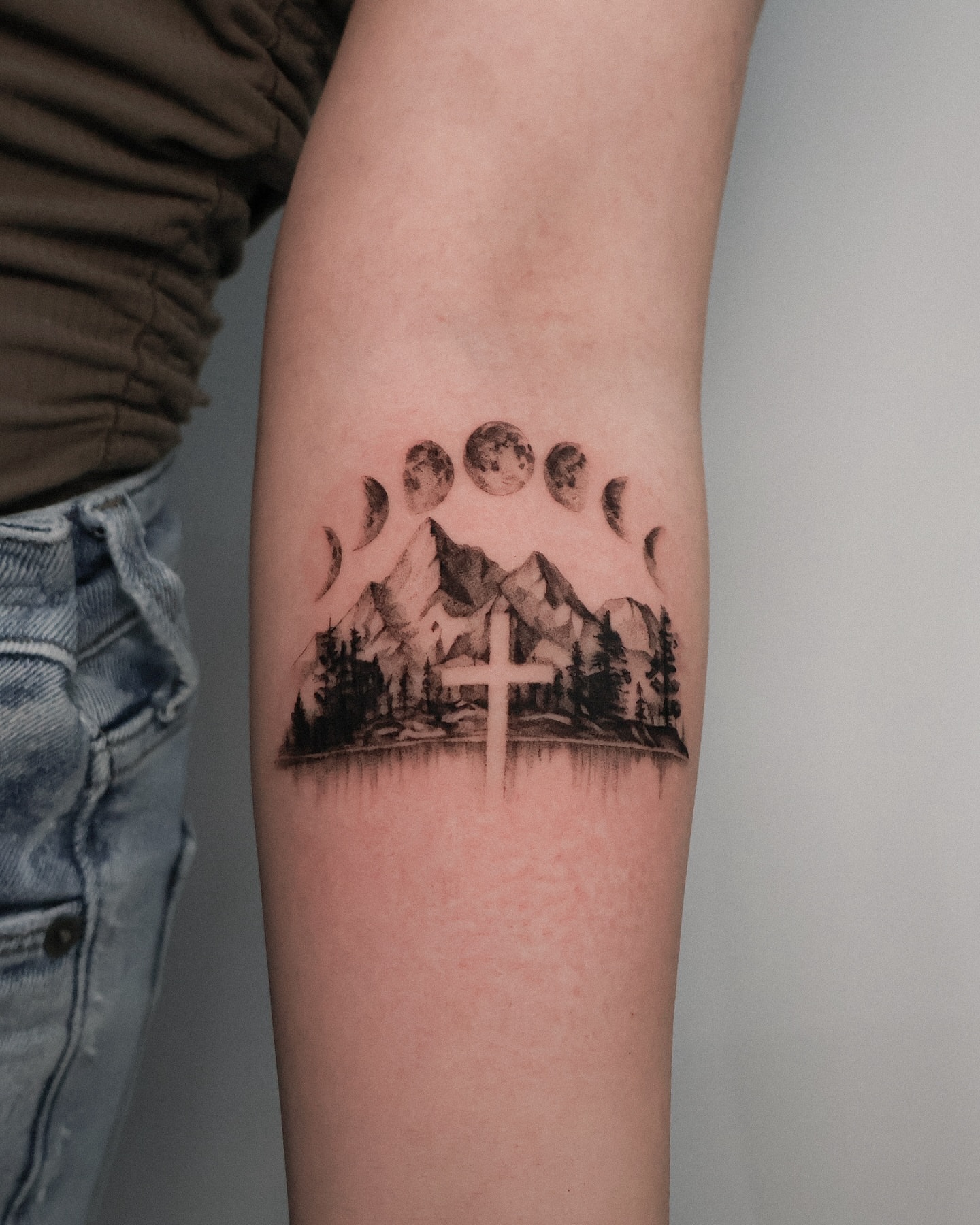 Mountains and moon phases realism tattoo on the forearm by Riley K Turner