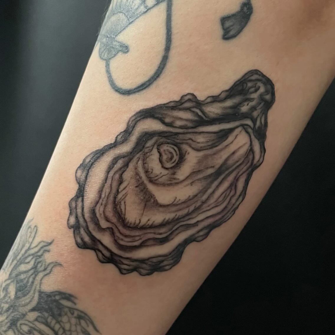 Oyster shell black and grey tattoo on the forearm by Hildur Blom, Seattle, Washington