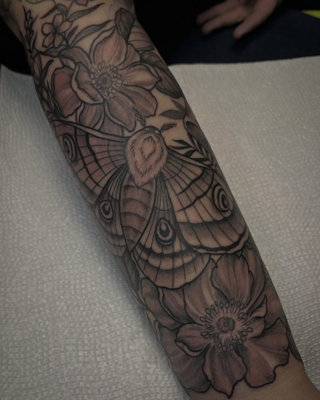 Moth and flowers realism tattoo on the forearm by JoDee Yates
