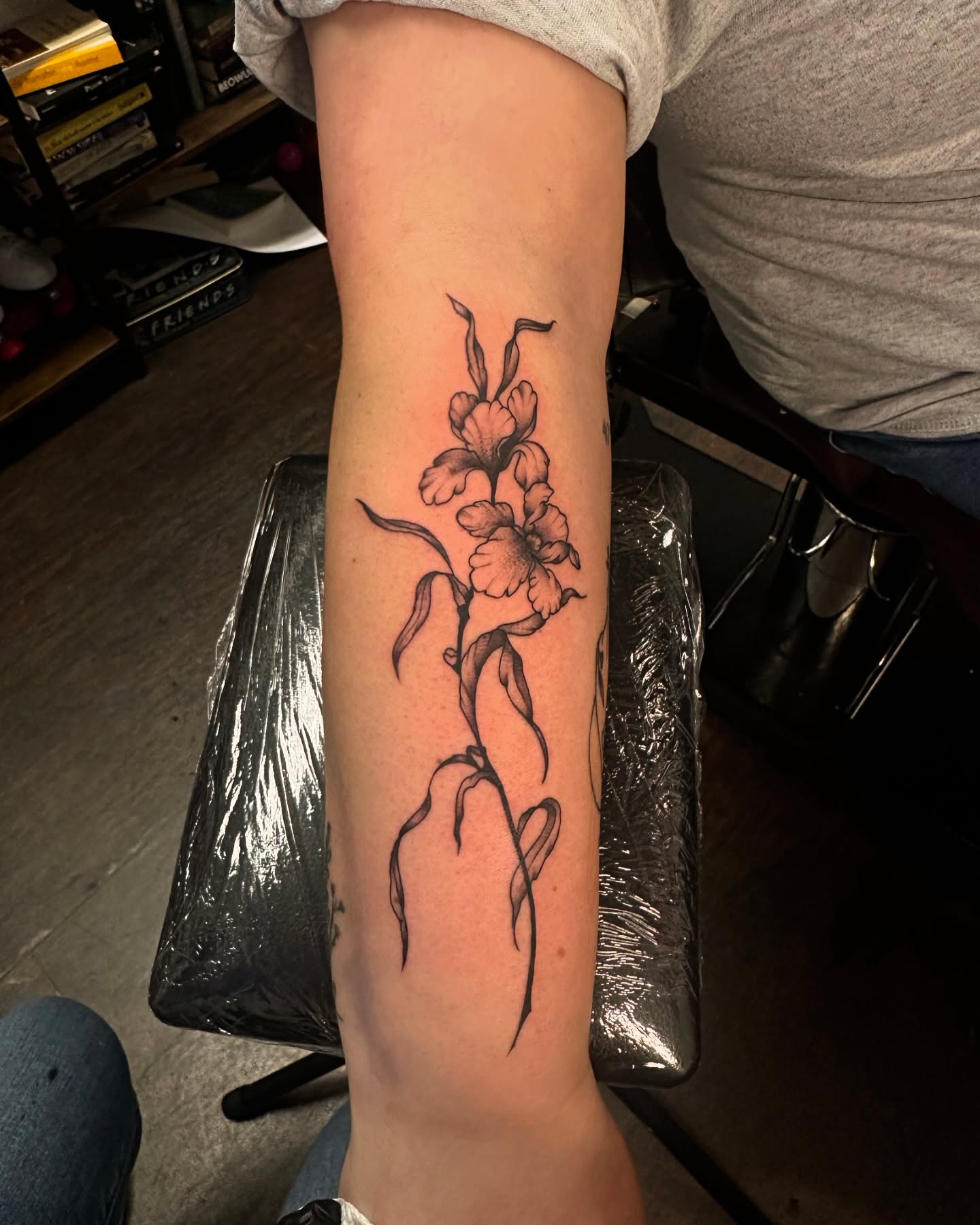 Gladiolus black and grey tattoo on the forearm by Kassie Perian