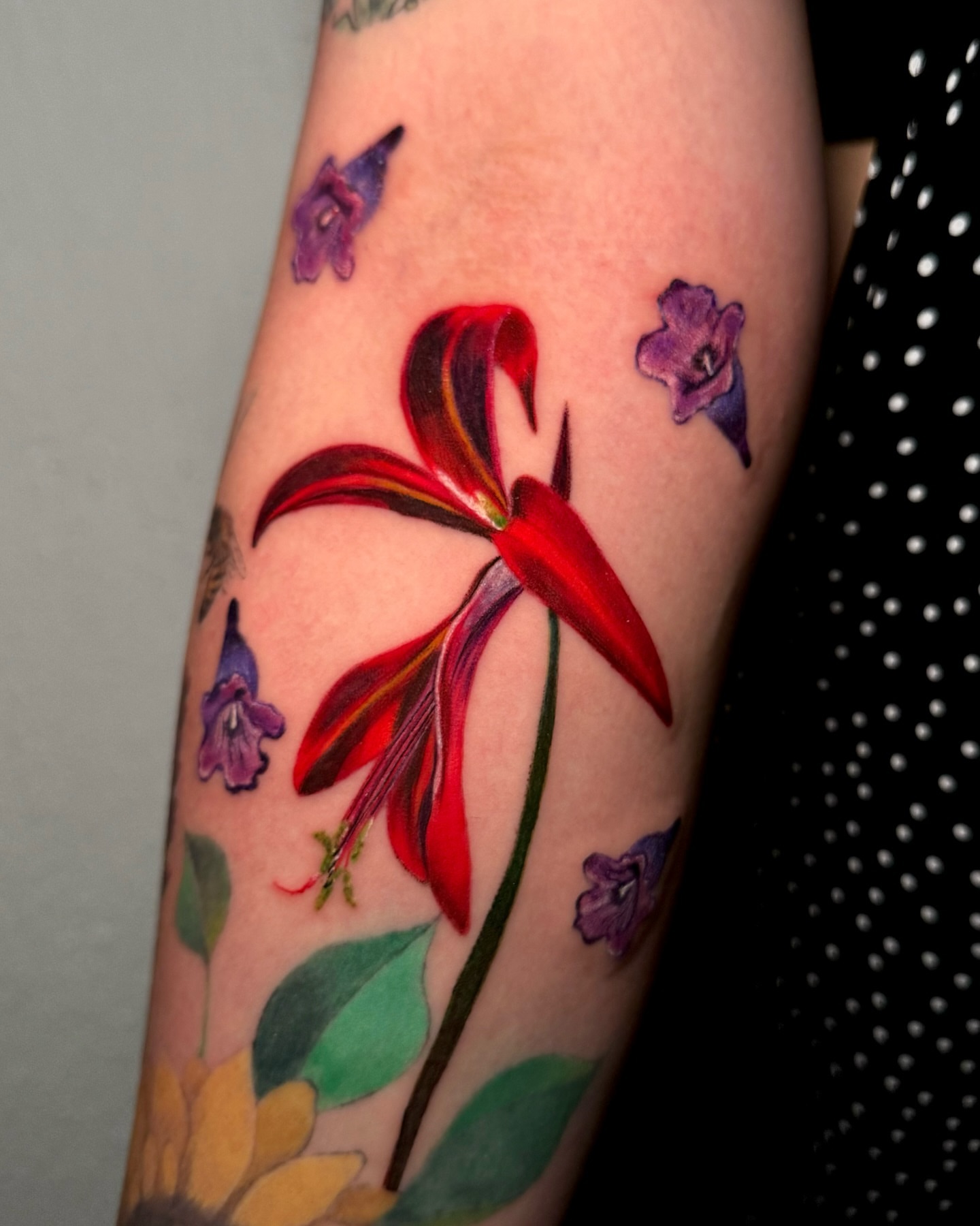 Red lily realism tattoo on the forearm by Mishel Castro