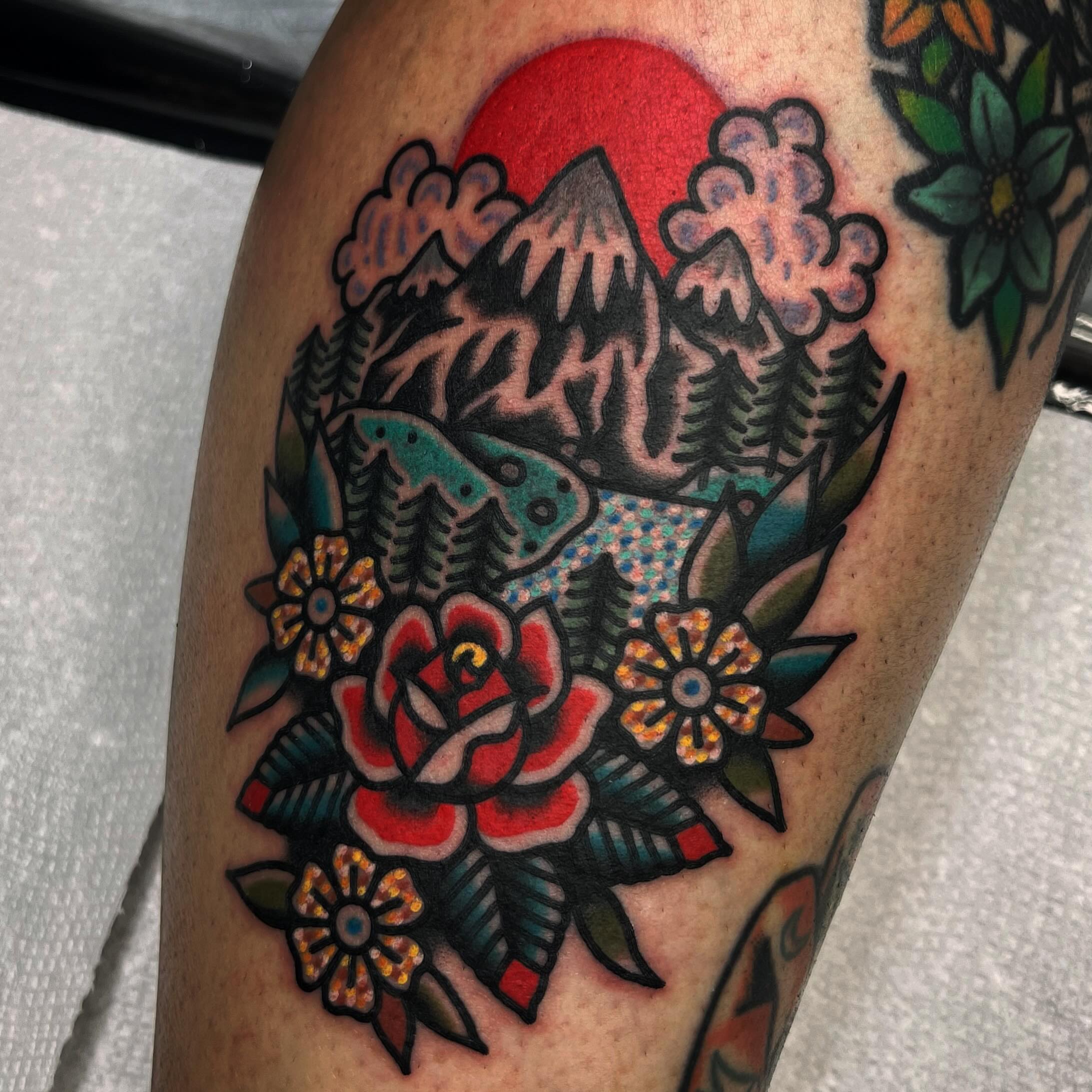 Mountain and floral bouquet American traditional tattoo on the thigh by Benjamin Ward