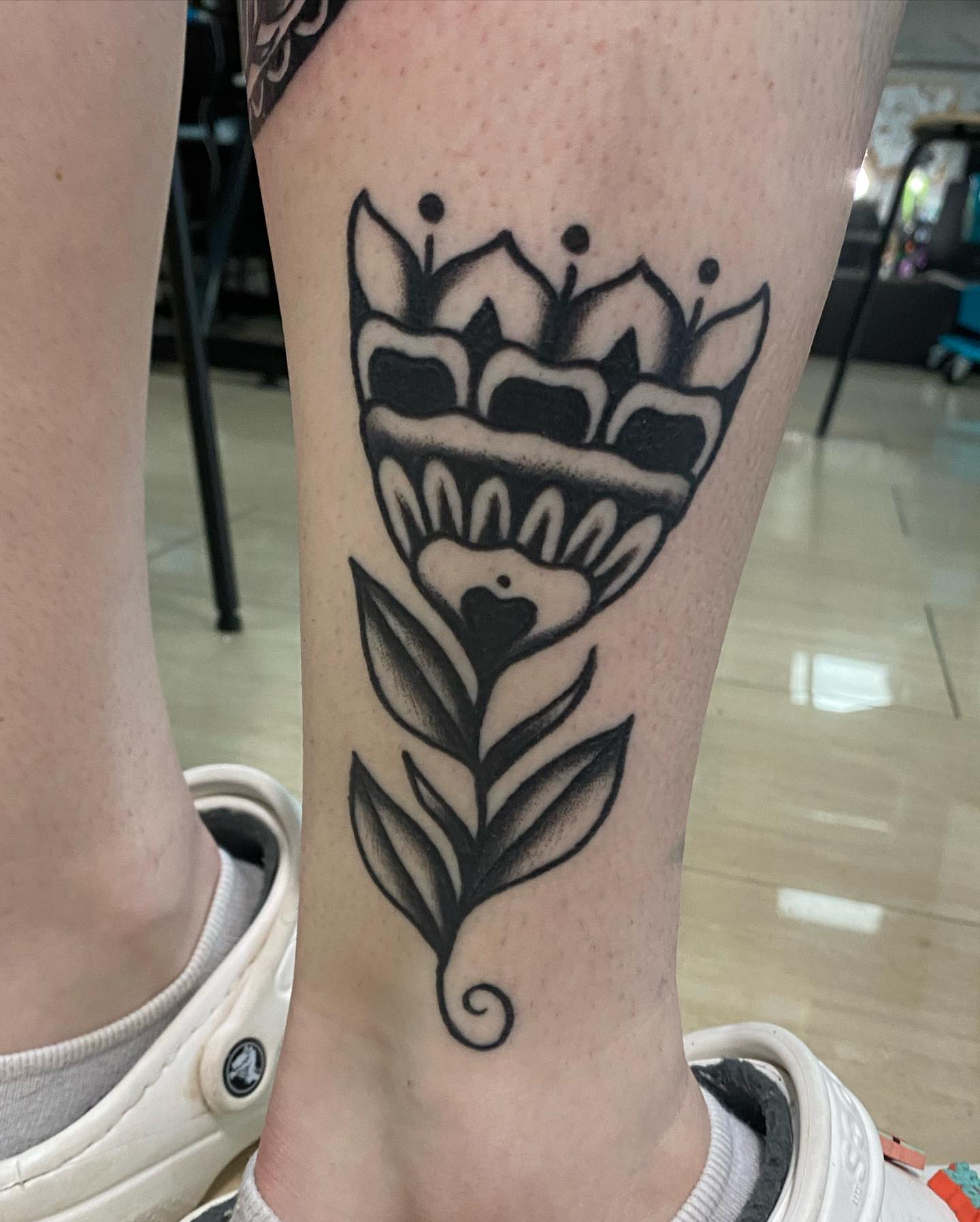 Floral crown black and grey tattoo on the calf by Shana