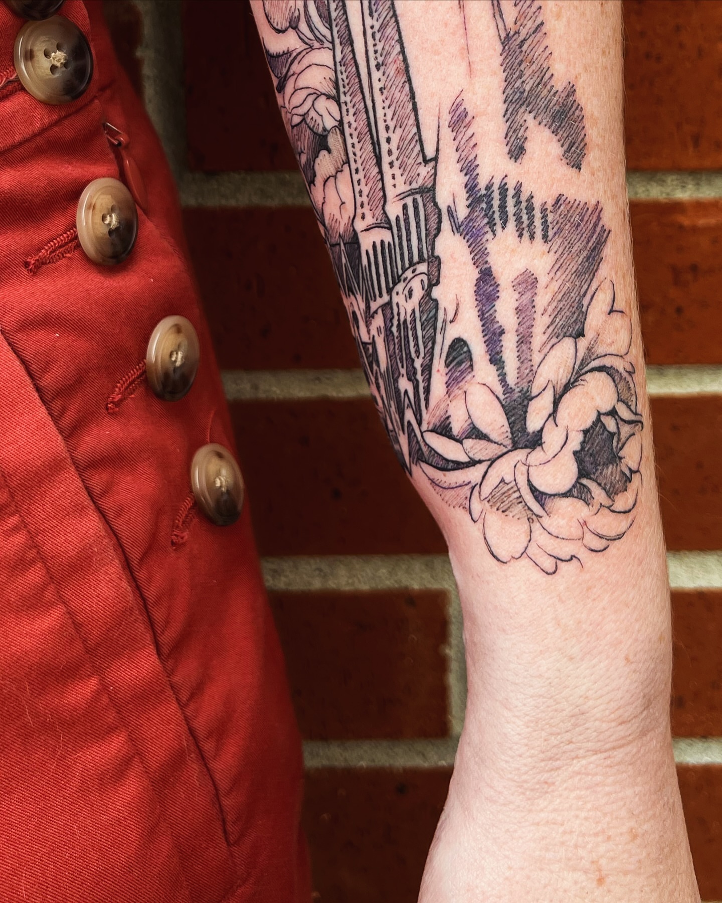 Building and floral black and grey tattoo on the forearm by Tattoos by Alli Wilcox