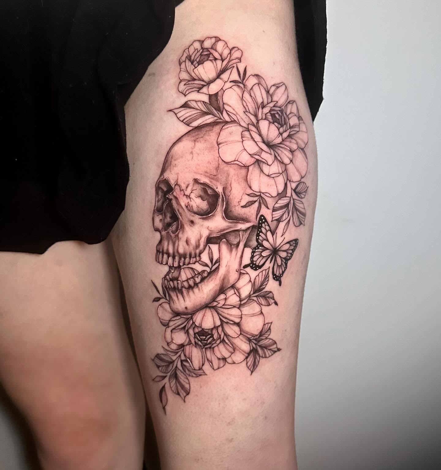 Skull with flowers realism tattoo on the thigh by Megan McKee Tattoo Artist