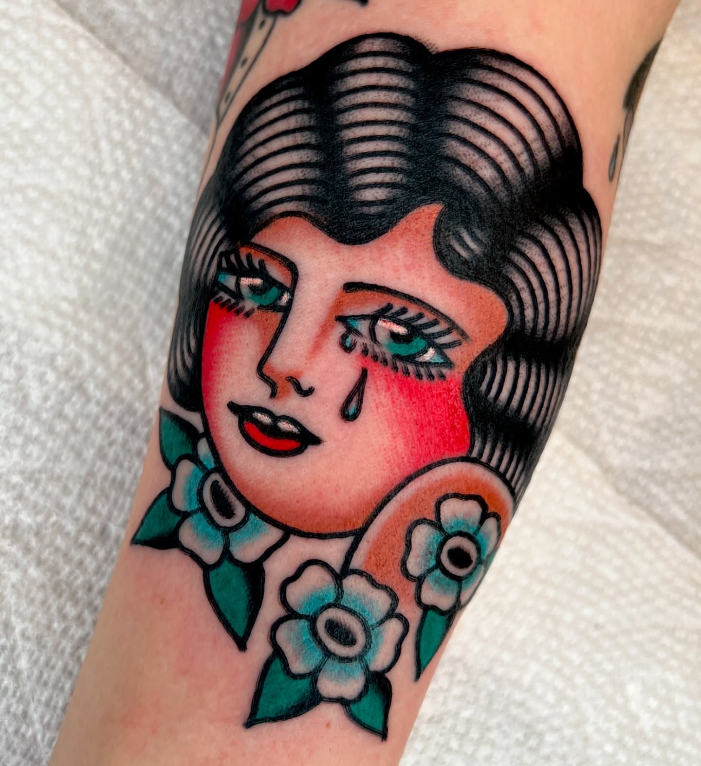 Woman with flowers American traditional tattoo on the forearm by Ian Jett