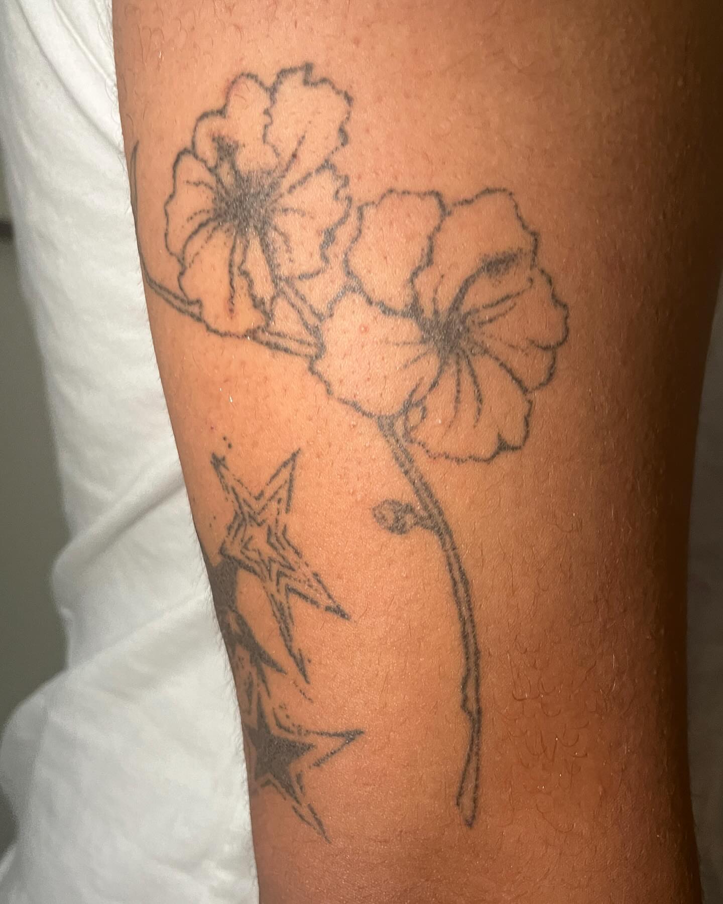 Flowers and stars black and grey tattoo on the forearm by hana