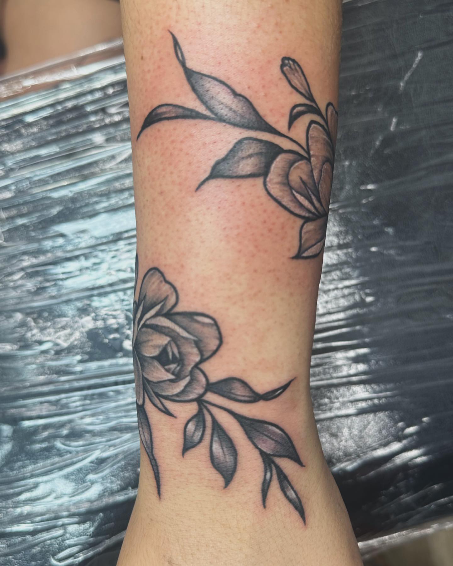 Flower and leaves black and grey tattoo on the forearm by Svetlana