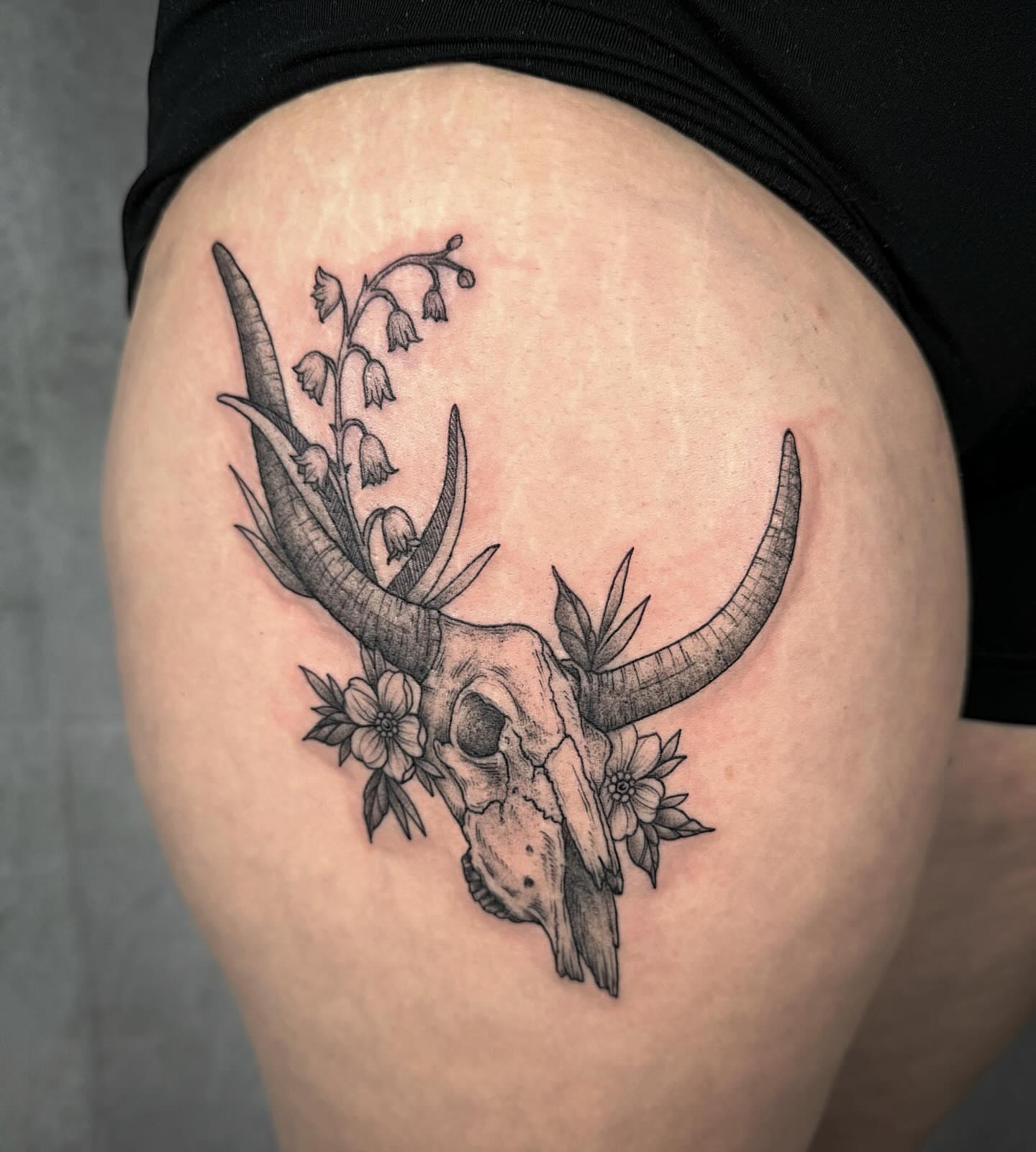 Deer skull with flowers black and grey tattoo on the thigh by Mallory Miller π³οΈβπ Eugene