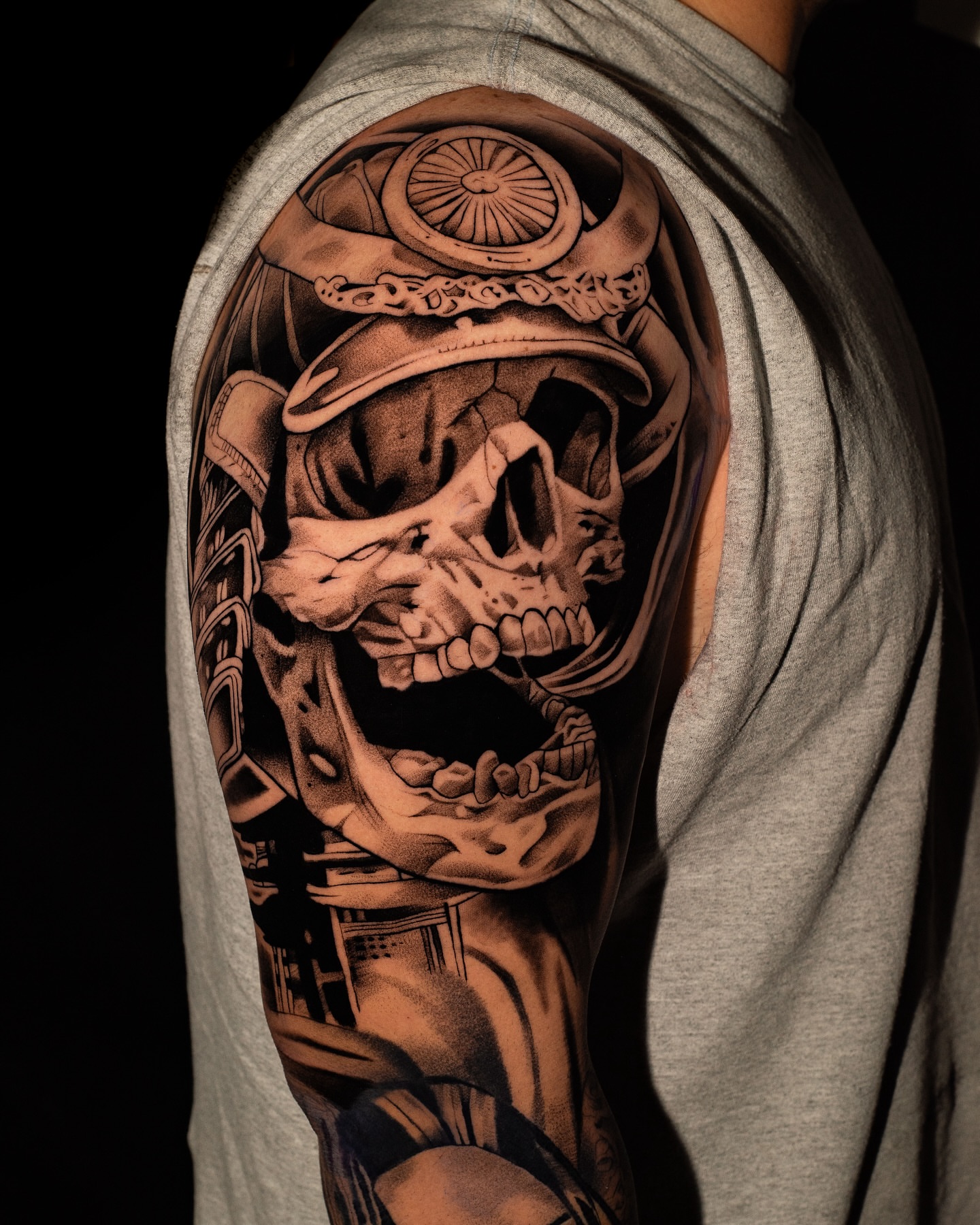 Skull wearing hat realism tattoo on the upper arm by Javier Ramos