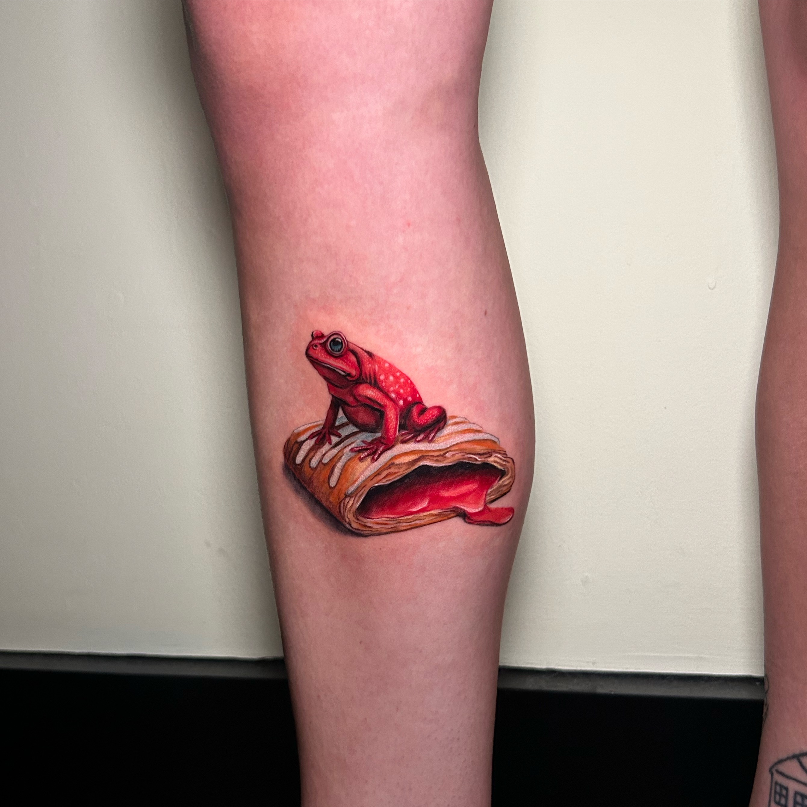 Red frog realism tattoo on the forearm by Tiffany Bauer