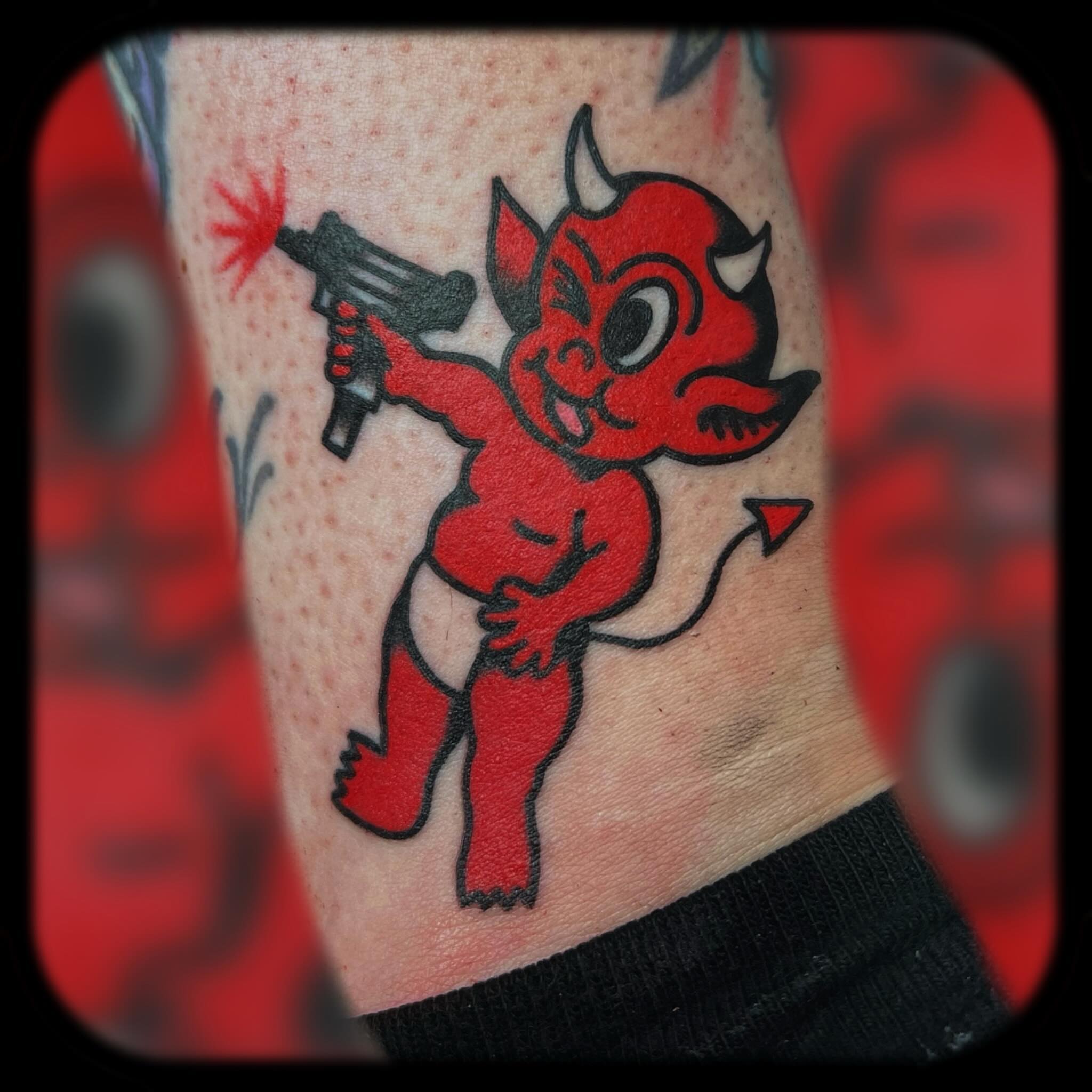 Red devil with gun American traditional tattoo on the forearm by Benjamin Ward