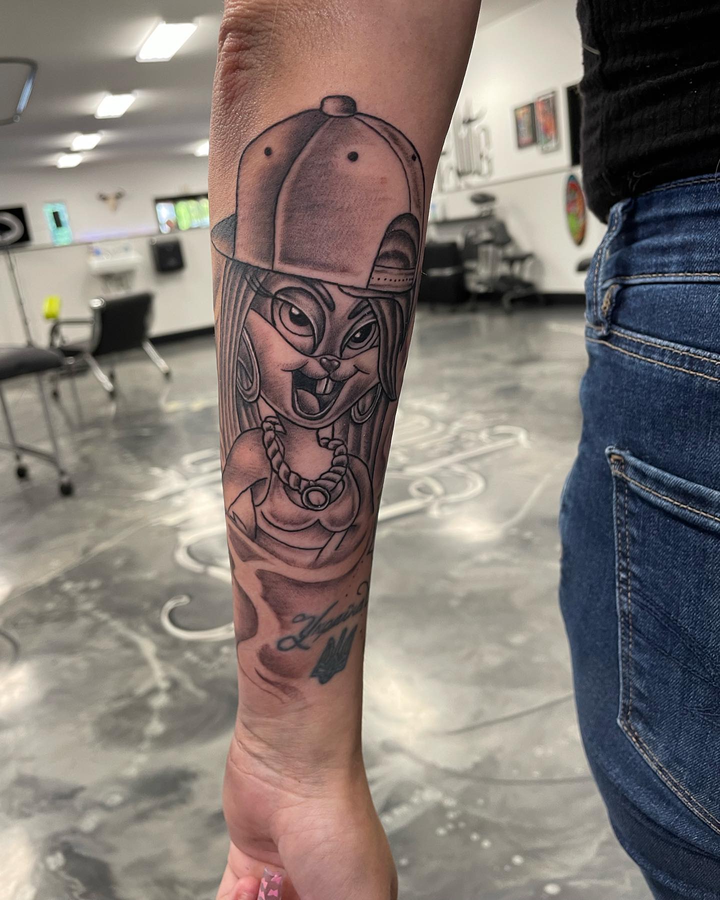 Cat wearing cap black and grey tattoo on the forearm by Brandon Anderson
