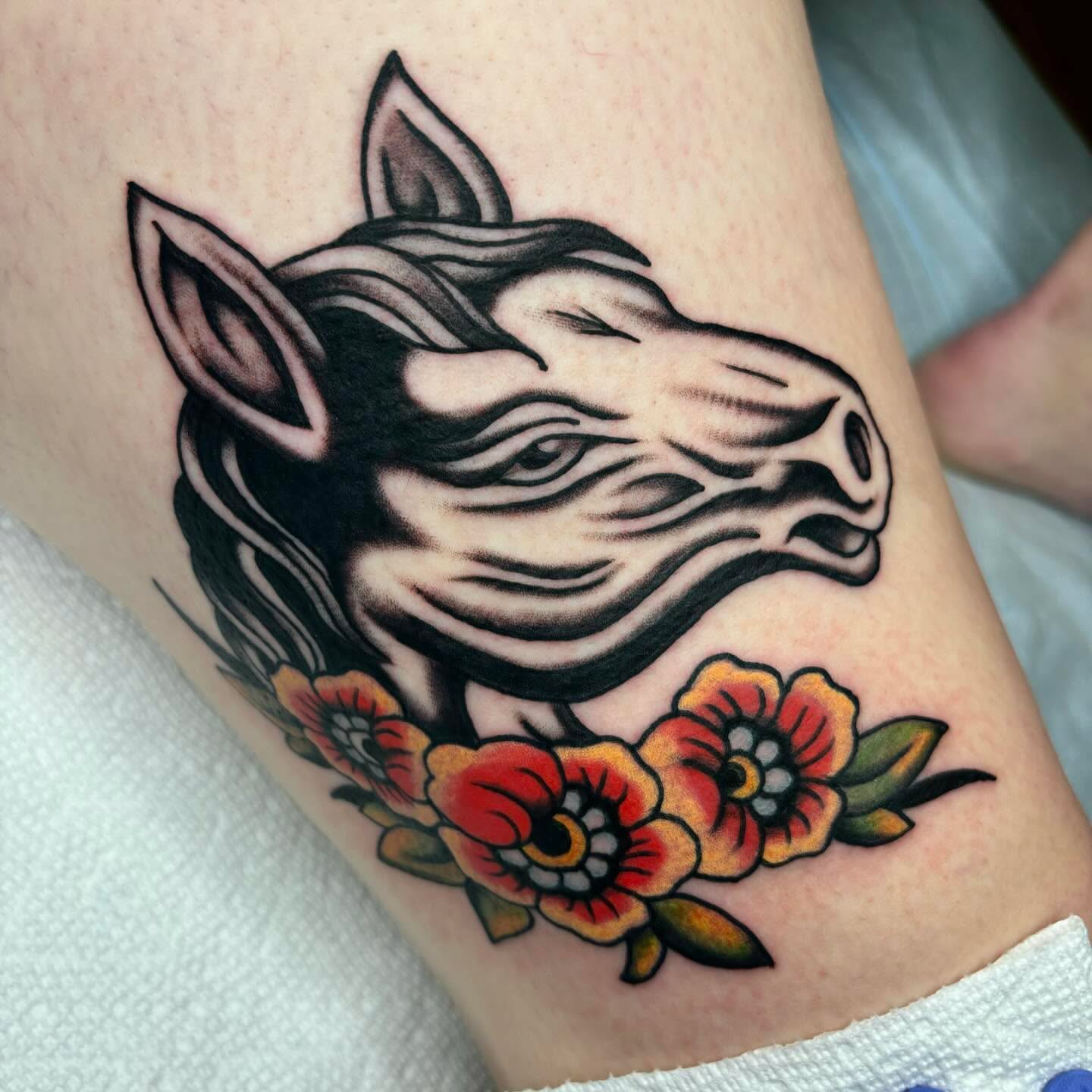 Zebra and flowers American traditional tattoo on the thigh by Emmy Gallagher