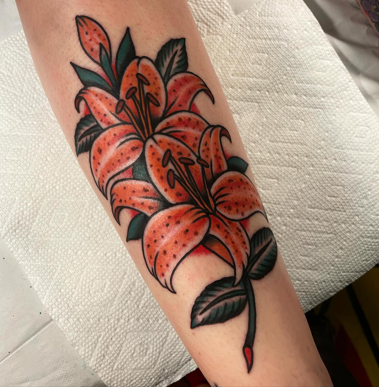 Lilies American traditional tattoo on the forearm by Mike Hudgins