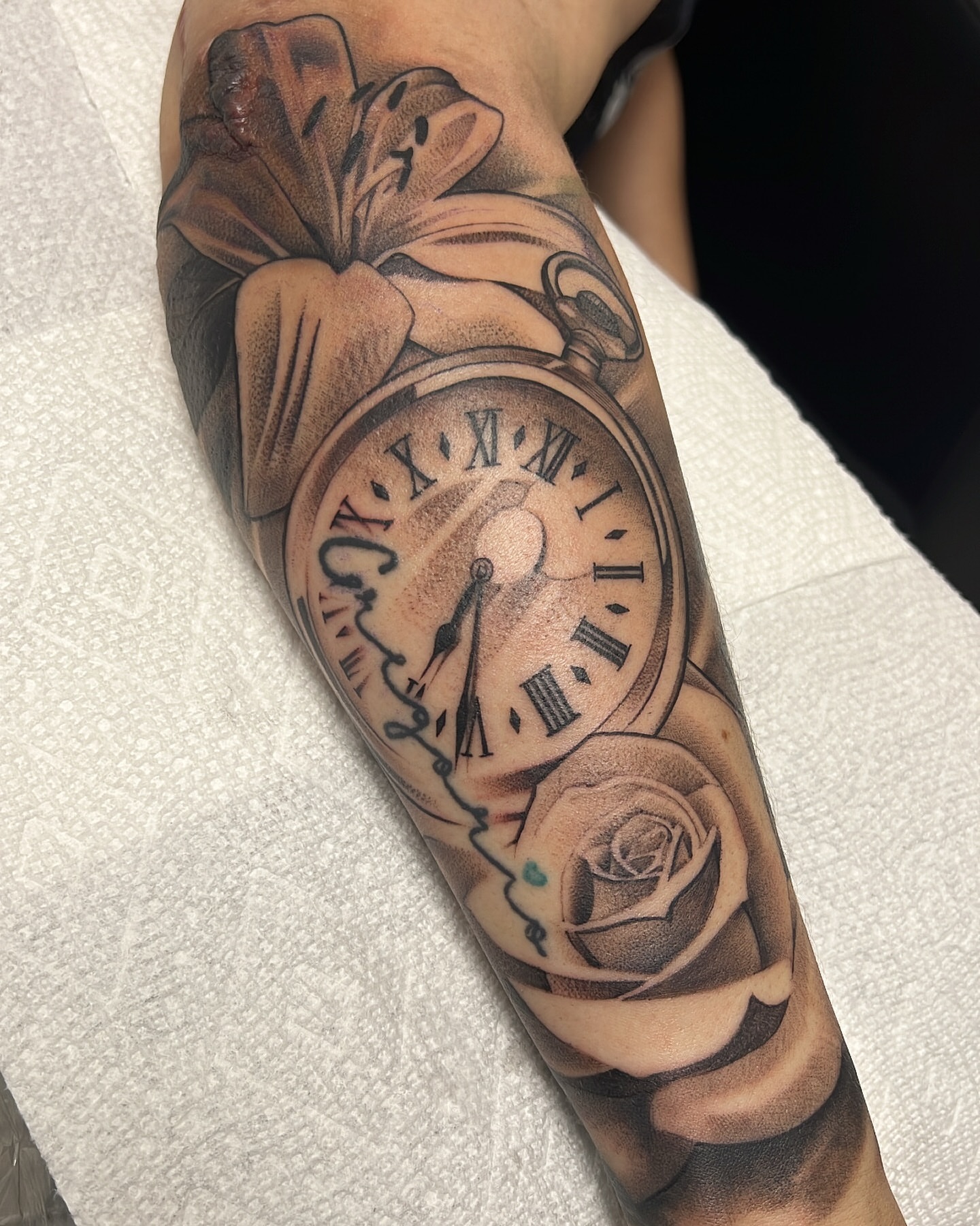 Clock and flower realism tattoo on the forearm by chris tattoo