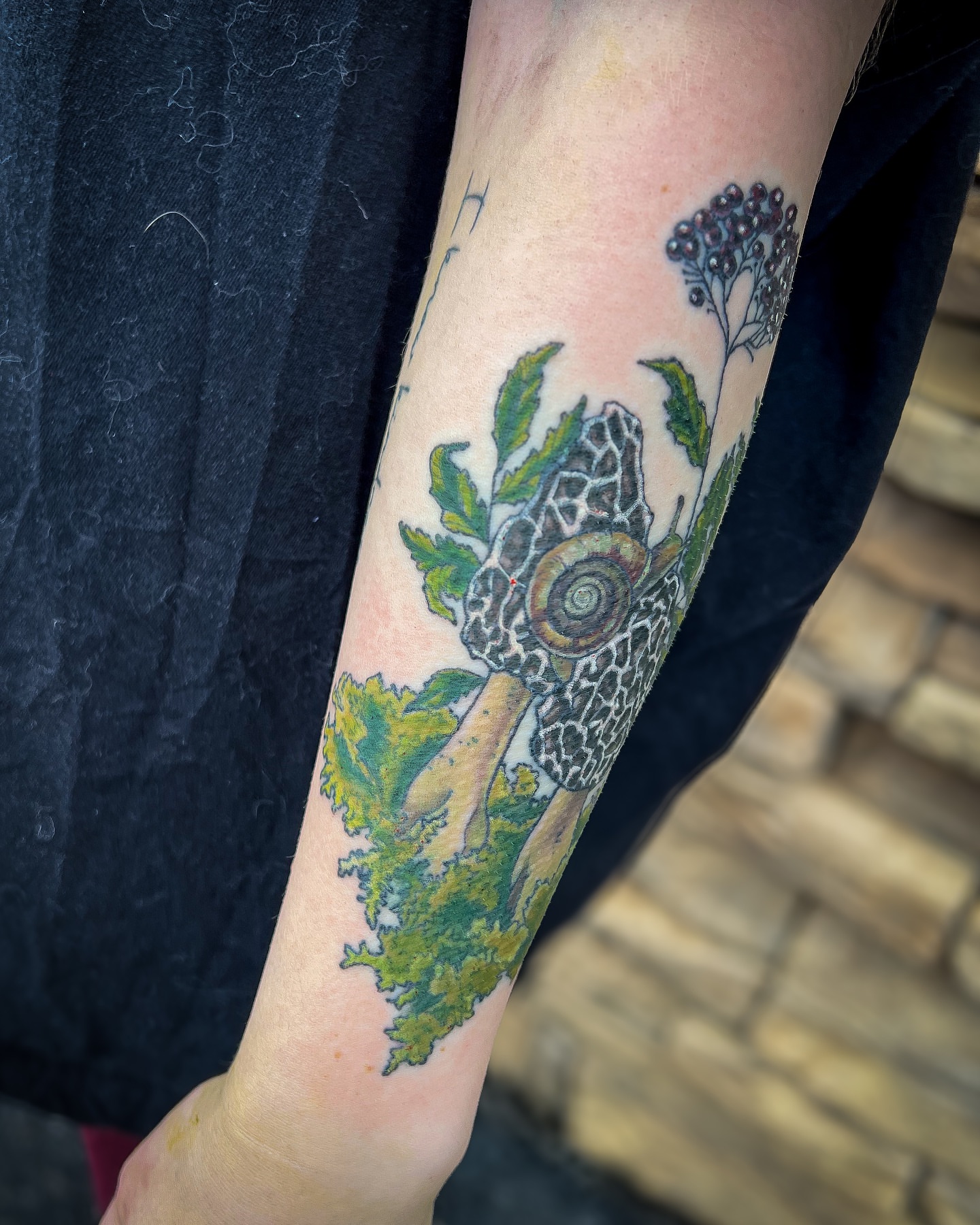 Snail and plant realism tattoo on the forearm by Reagan Sutton
