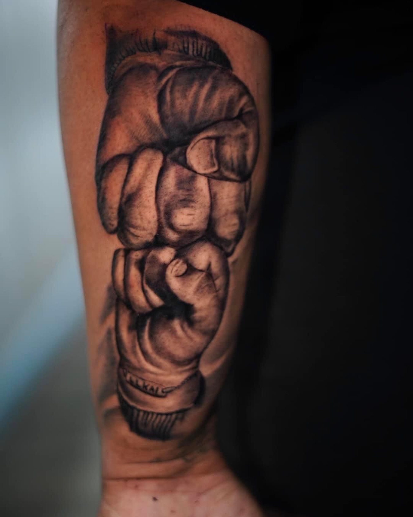 Fist black and grey tattoo on the forearm by Sly Davis