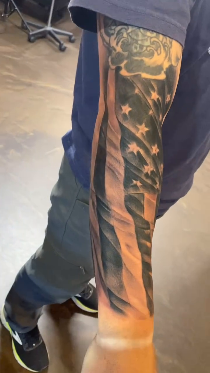 American flag realism tattoo on the upper arm by Cody Wolfe