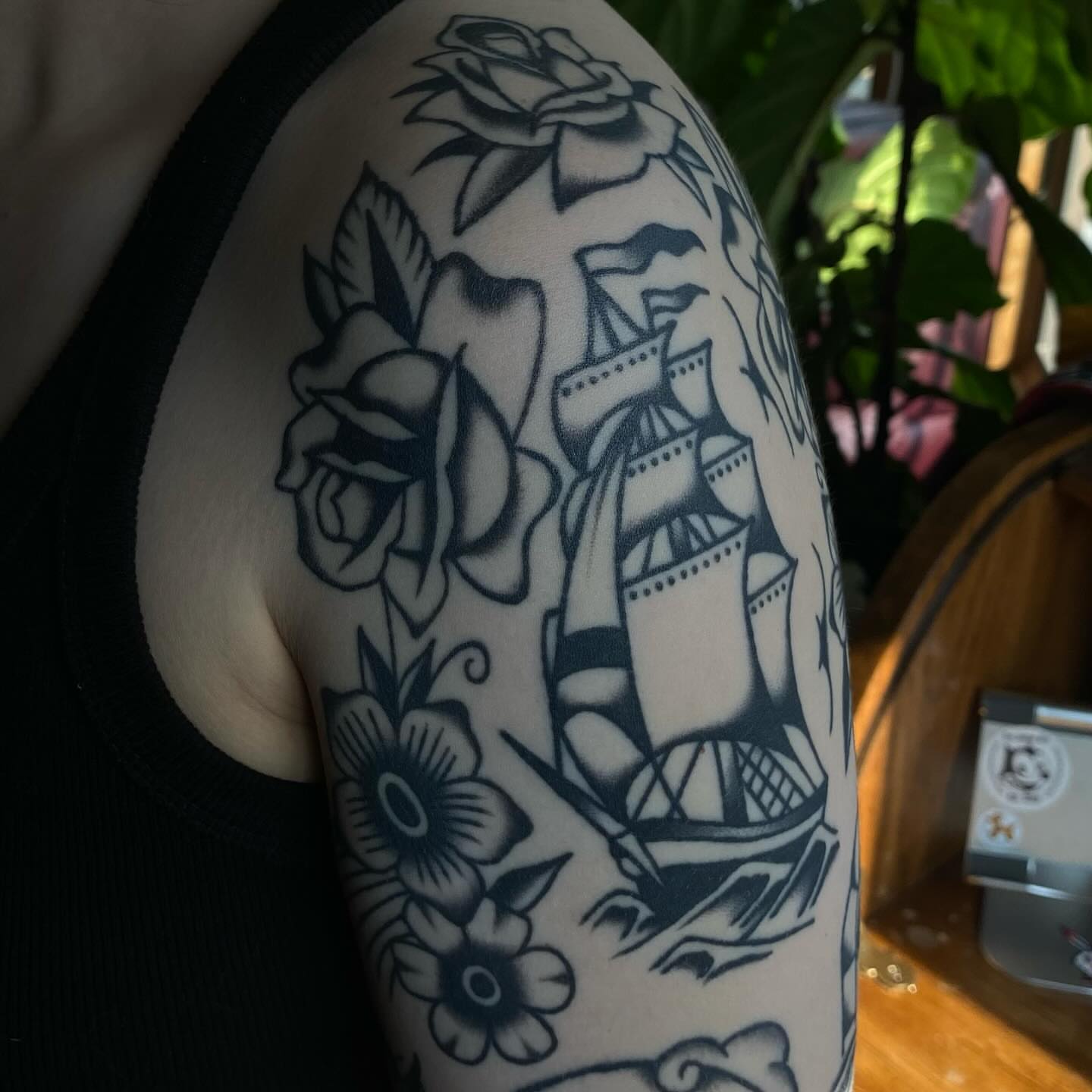 Ship and roses American traditional tattoo on the upper arm by Erin Chambers