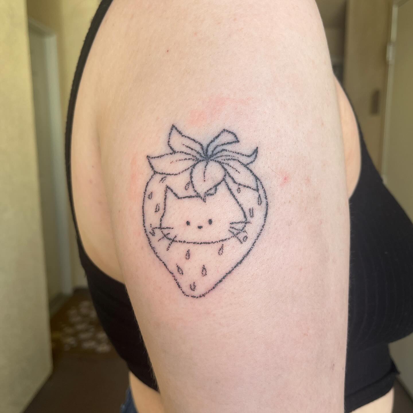 Cat inside strawberry dotwork tattoo on the shoulder by hana