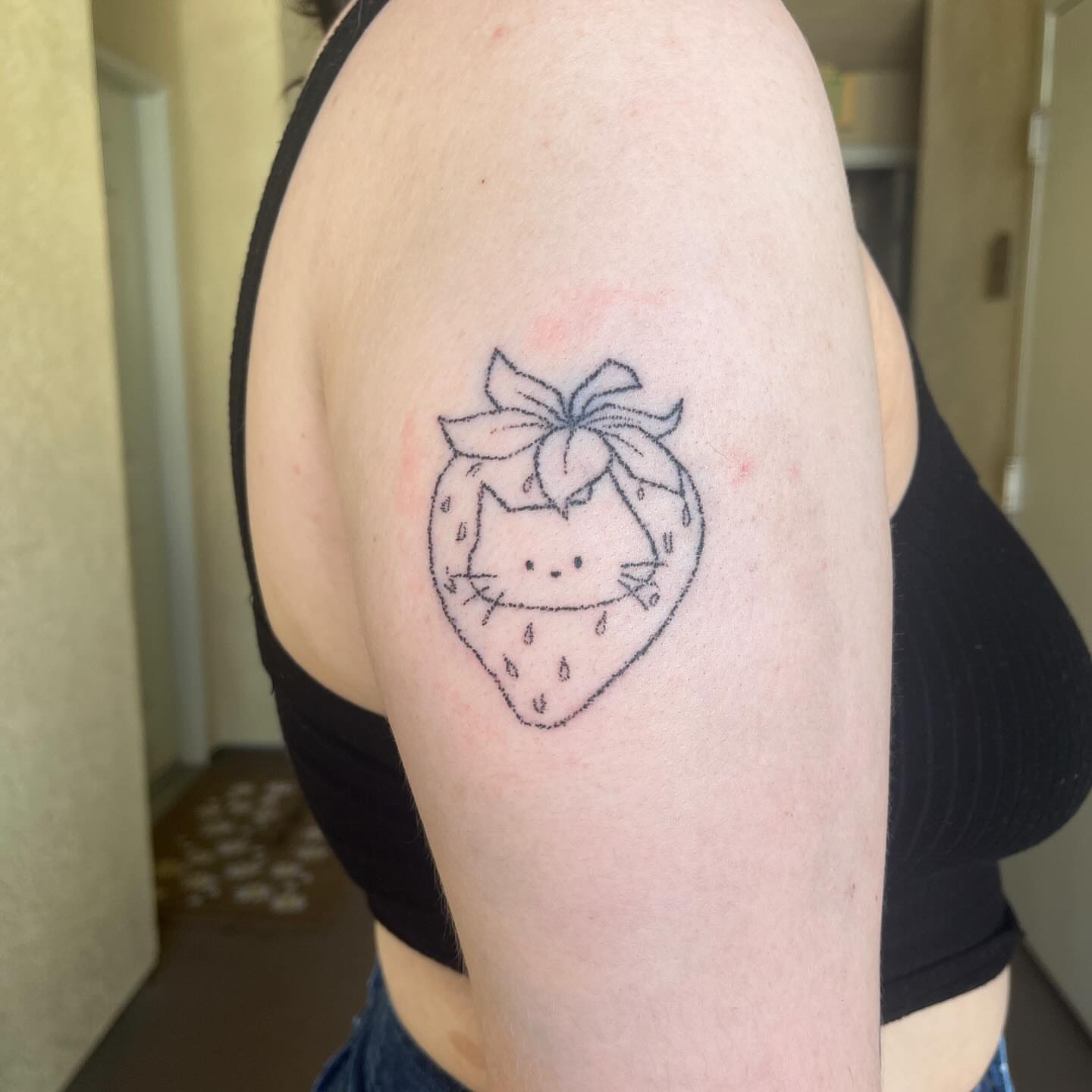 Strawberry cat dotwork tattoo on the shoulder by hana