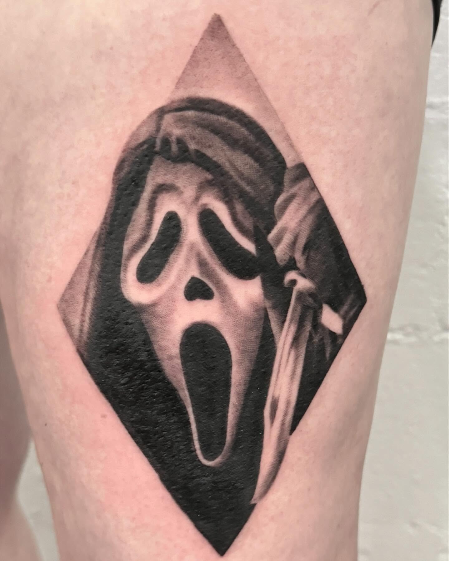 Scream mask black and grey tattoo on the thigh by Drew Foster, Toledo, Ohio