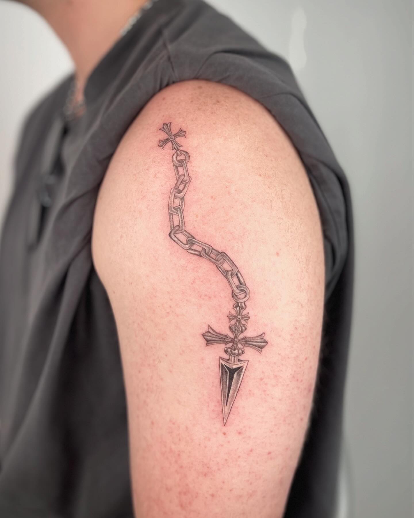 Chain and cross black and grey tattoo on the shoulder by Jennifer Fuster