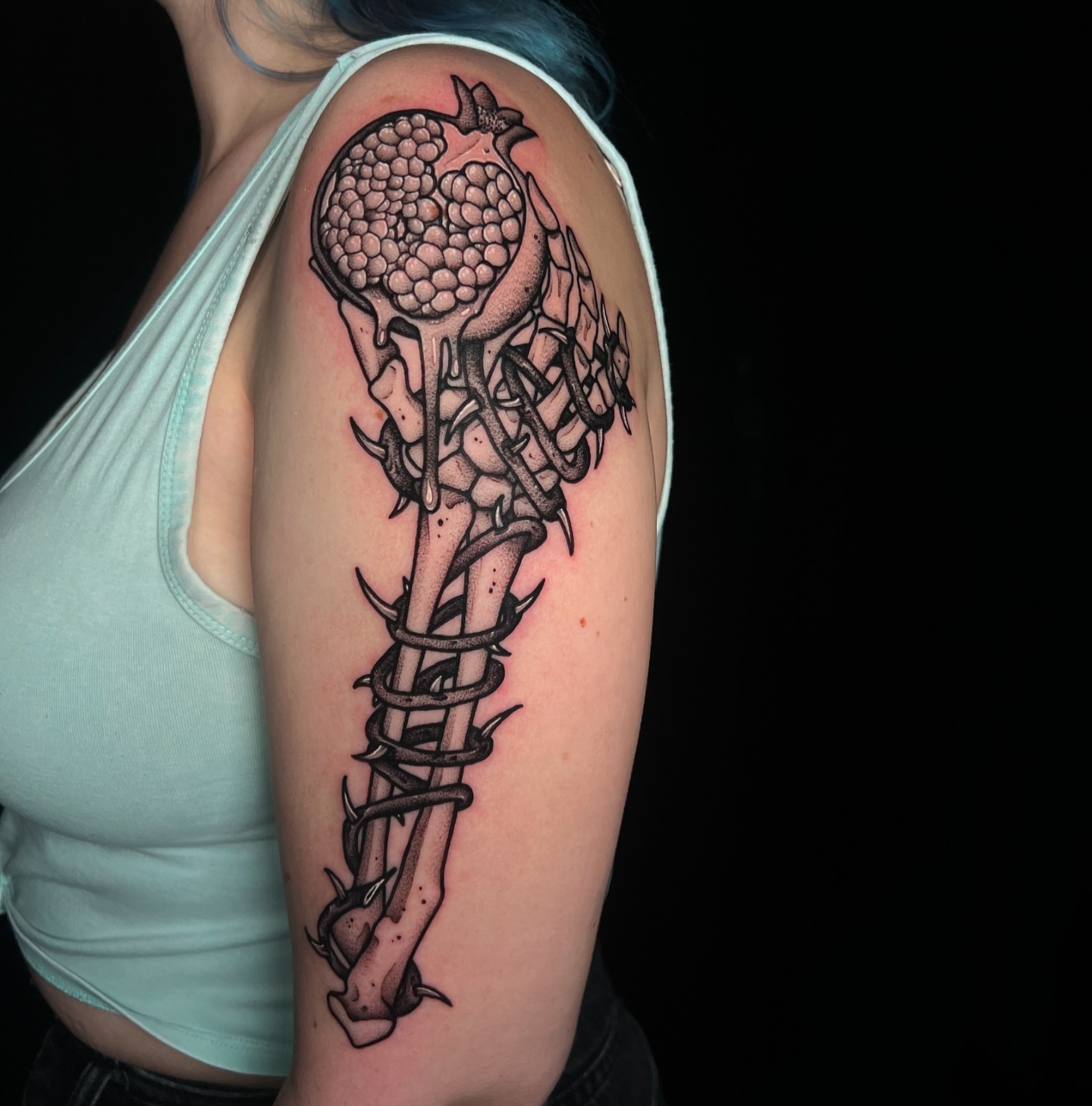 Bone and pomegranate realism tattoo on the upper arm by Pam Sanders