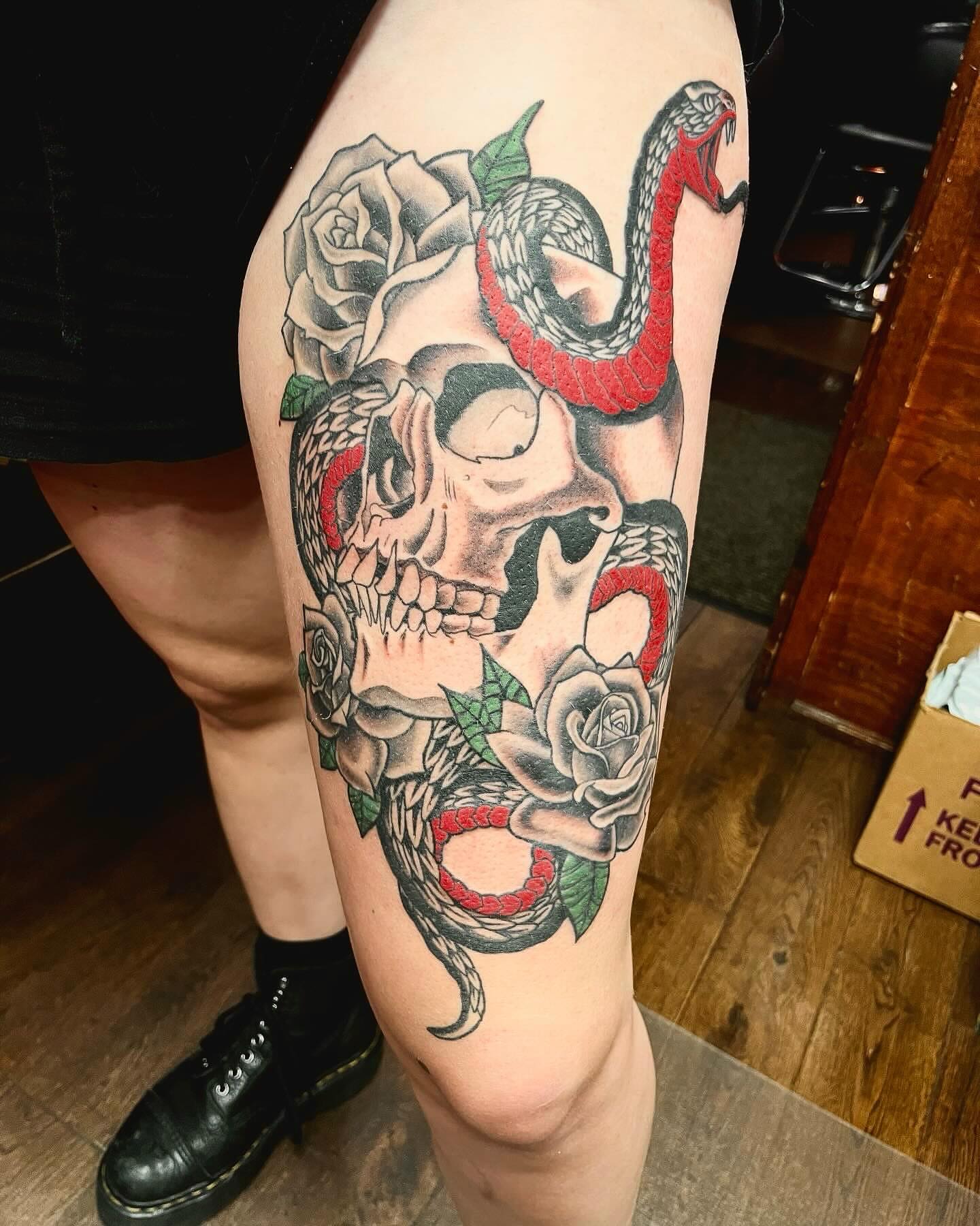 Skull with roses and snakes American traditional tattoo on the thigh by Kenny Buck