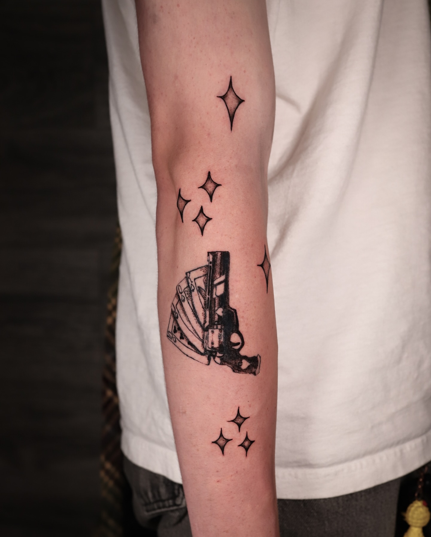 Gun and stars black and grey tattoo on the forearm by Kipling Mcclellan