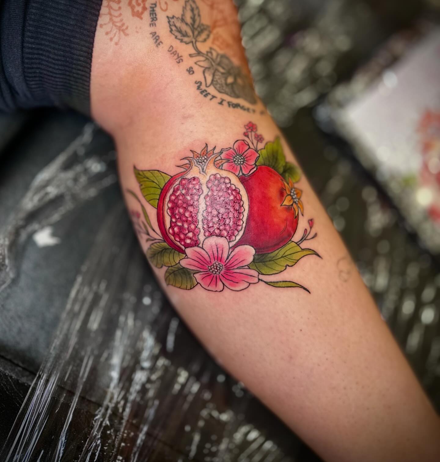 Pomegranate and flowers realism tattoo on the forearm by Jewels, St. George, Utah
