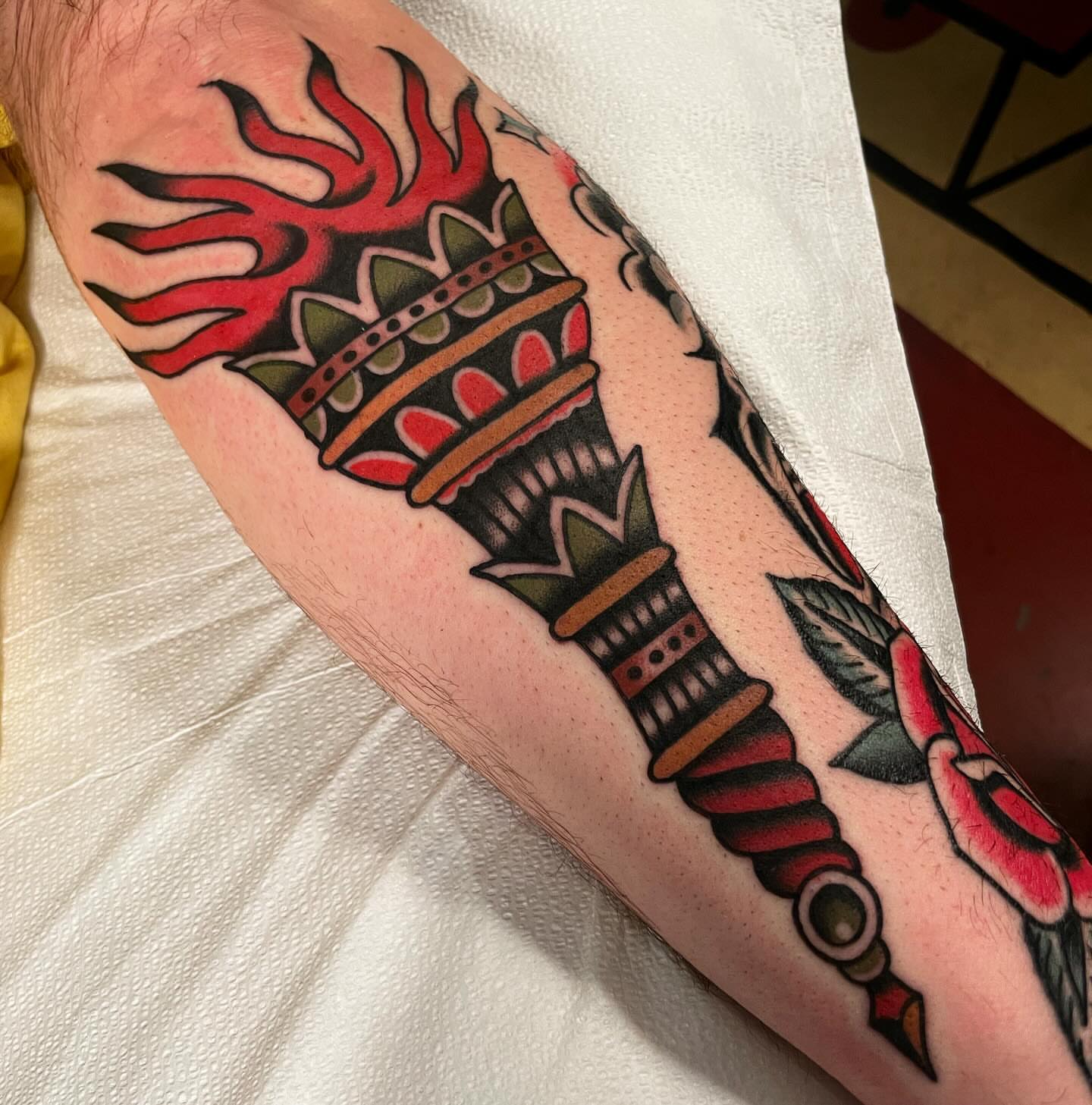 Torch with flame American traditional tattoo on the forearm by Mike Hudgins