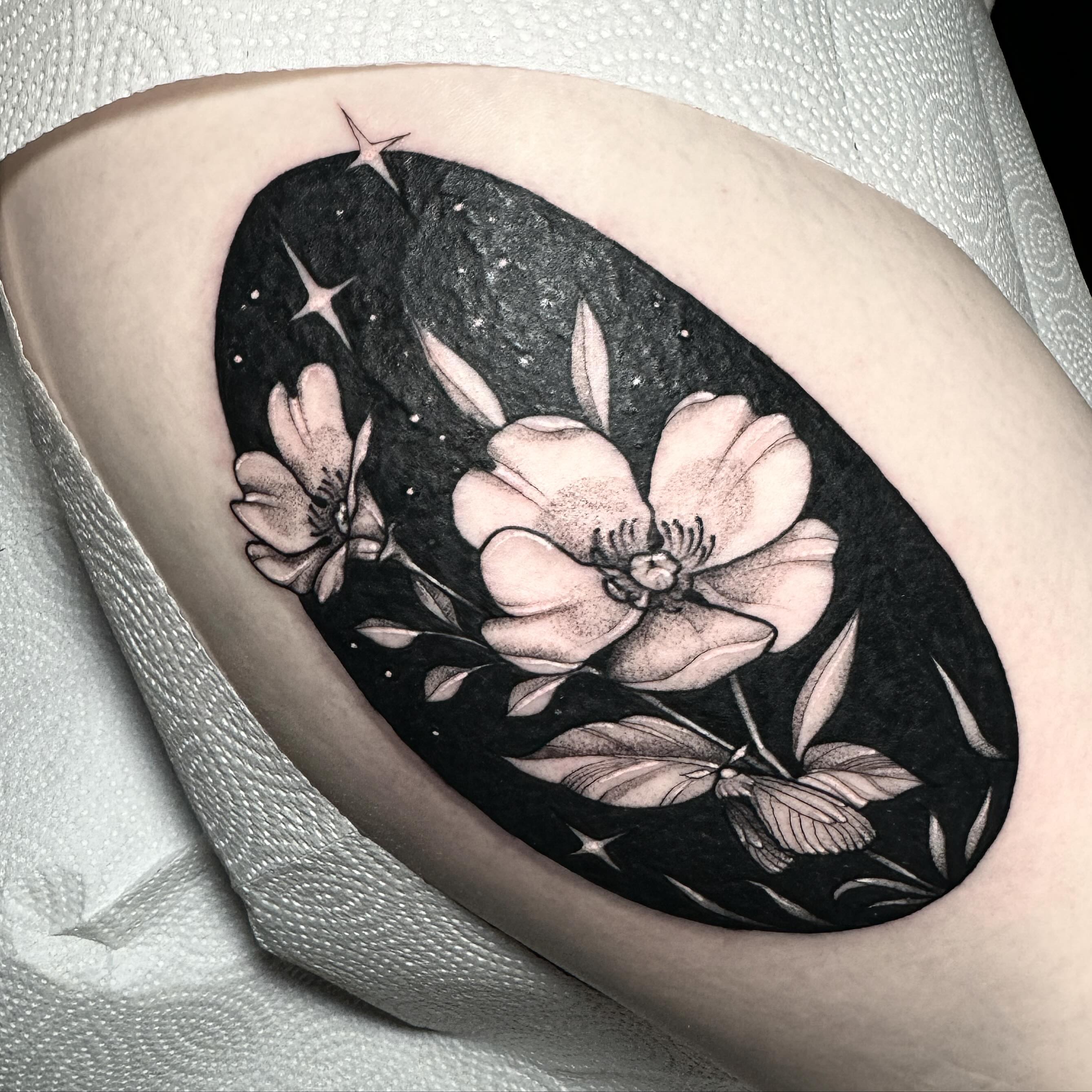 Flowers and night sky realism tattoo on the thigh by 𝔈𝔯𝔦𝔫 𝔊𝔦𝔩𝔩𝔦𝔩𝔞𝔫𝔡, Springfield, Ohio