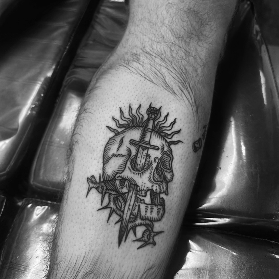 Skull with cross black and grey tattoo on the forearm by Kassie Perian