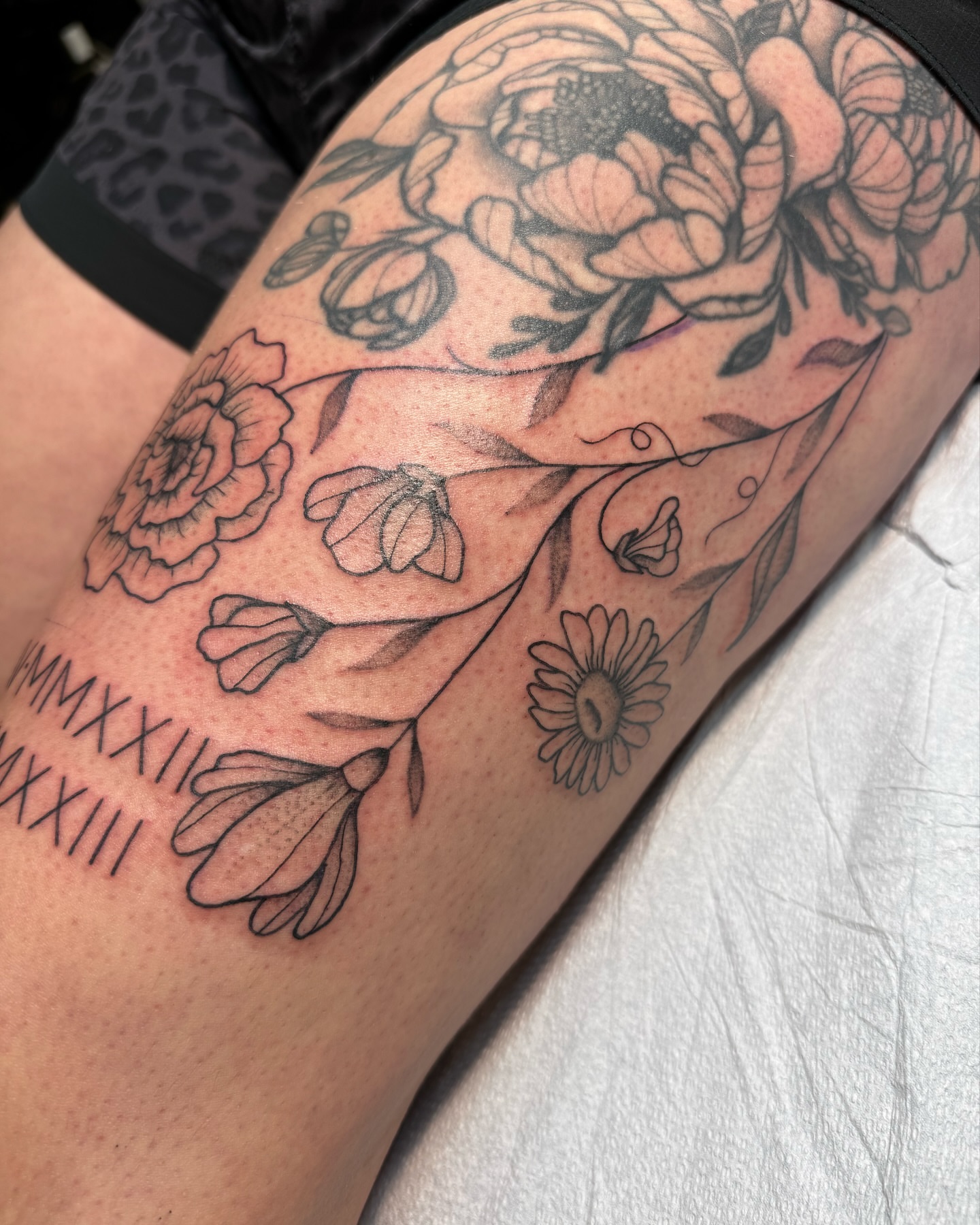 Floral arrangement black and grey tattoo on the thigh by Mazie