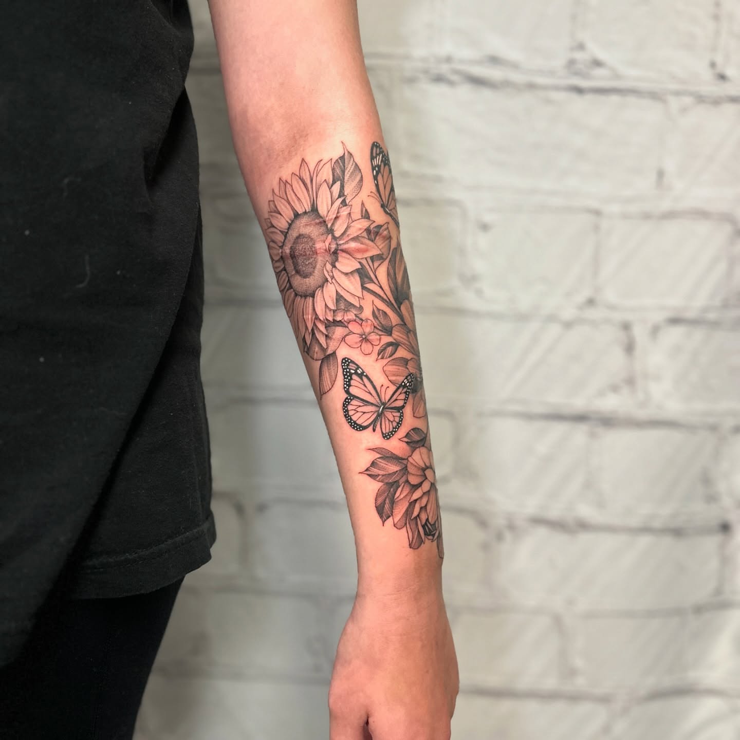 Sunflower and butterfly black and grey tattoo on the forearm by Stephen Hansen