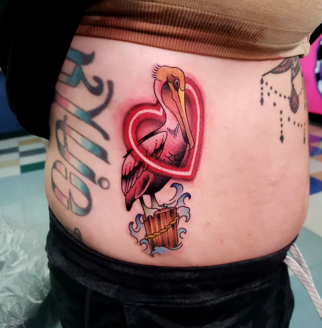 Pelican and heart American traditional tattoo on the torso by Jake Lee
