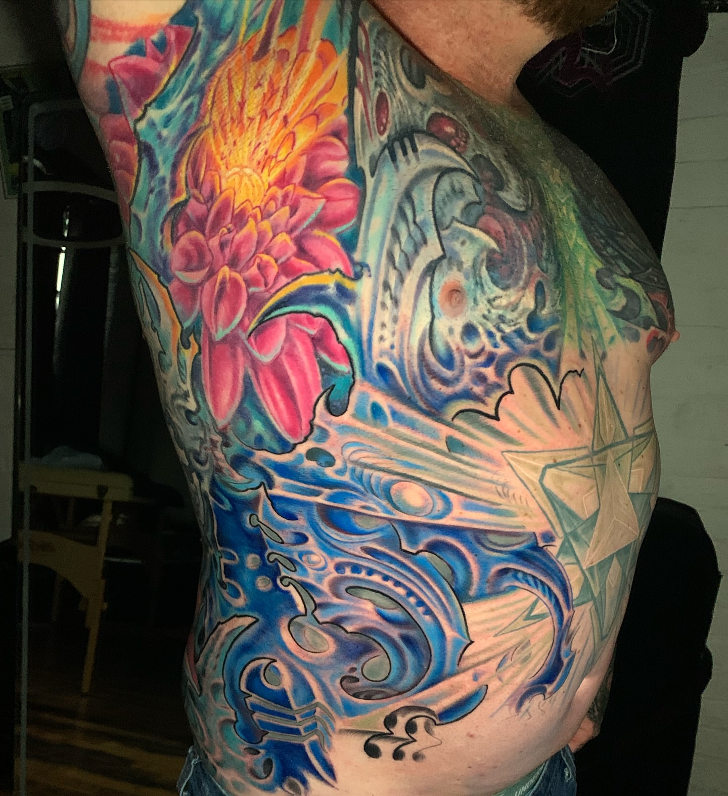 Abstract floral and mechanical design new school tattoo on the chest by Phil Robertson