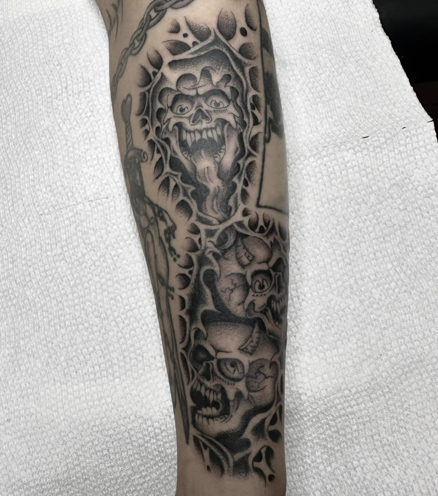 Skulls and chains dark realism tattoo on the forearm by Elijah Edwards